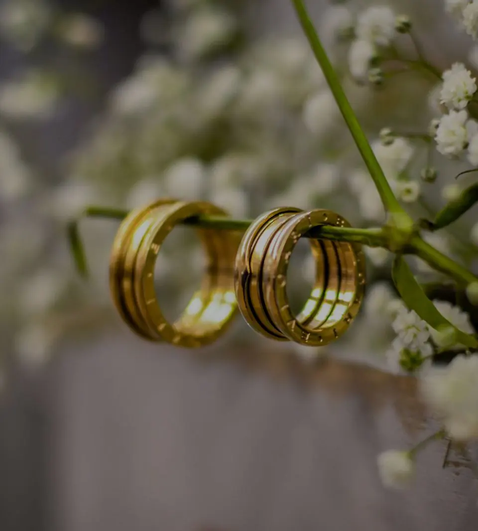 Par de alianças de ouro presas a um ramo de flores